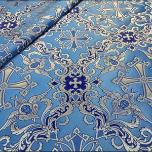 May include: Blue fabric with a gold and blue cross pattern. The fabric has a brocade texture and is perfect for upholstery or crafts.
