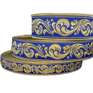 Peut inclure: Trois bobines de ruban décoratif bleu et doré. Le ruban présente un motif floral doré sur fond bleu. Les bobines sont empilées, la plus grande étant à la base. Idéal pour les travaux manuels.