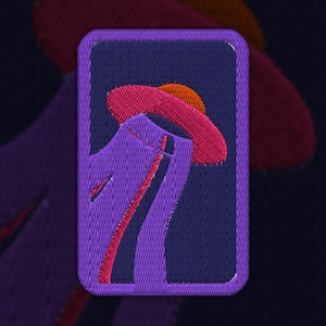 Puede incluir: Parche bordado de color morado con un diseño de sombrero rosa y naranja. El sombrero está inclinado y tiene un ala ancha. El parche está rodeado por un borde azul oscuro.