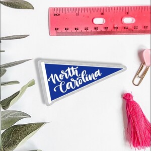 May include: A blue pennant with white text that reads "North Carolina".