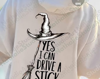 Könnte beinhalten: Ein weißer Kapuzenpullover mit einer schwarz-weißen Hexenhut- und Besen-Grafik. Der Text "YES I CAN DRIVE A STICK" befindet sich unter dem Hut. Geeignet für Halloween- oder Hexen-Themenkleidung.