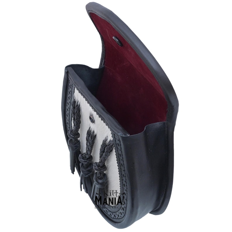 May include: A black leather sporran with a white fur flap and black braided tassels. The sporran is open and the inside is lined with red fabric.