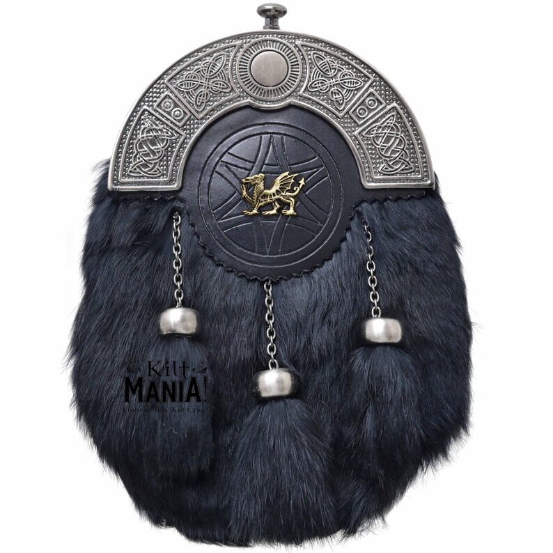 Puede incluir: Un sporran de kilt negro con un dise&ntilde;o celta plateado y un emblema de drag&oacute;n dorado. El sporran tiene un cuerpo de piel con tres borlas decorativas y detalles de cadena plateada. El texto "Kilt MANIA!" es visible.