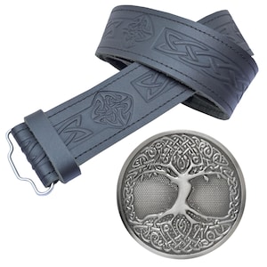 Peut inclure: Une ceinture en cuir noir avec des motifs de nœuds celtiques en relief et une boucle argentée représentant un arbre de vie. La ceinture est présentée débouclée, avec la boucle à côté.