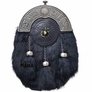 Puede incluir: Una sporran de piel negra con una parte superior decorativa de metal plateado y borlas. La sporran presenta una parte delantera de cuero con un emblema de lat&oacute;n. El texto "Kilt MANIA!" es visible en la parte inferior izquierda.