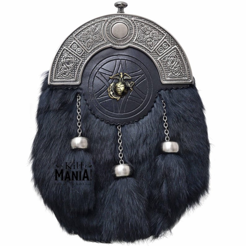 Puede incluir: Una sporran de piel negra con una parte superior decorativa de metal plateado y borlas. La sporran presenta una parte delantera de cuero con un emblema de lat&oacute;n. El texto "Kilt MANIA!" es visible en la parte inferior izquierda.