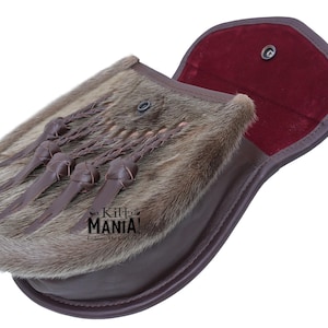 May include: A brown leather sporran with a fur flap and a red velvet lining. The sporran has a braided strap with tassels and a metal snap closure.