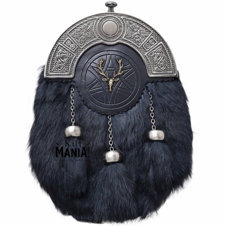 Puede incluir: Un sporran de piel negra con una parte superior de metal plateado y detalles decorativos. El sporran presenta una parte delantera de cuero negro con un emblema de ciervo dorado. Cadenas y borlas plateadas cuelgan de la parte inferior. El texto "Kilt Mania" es visible.