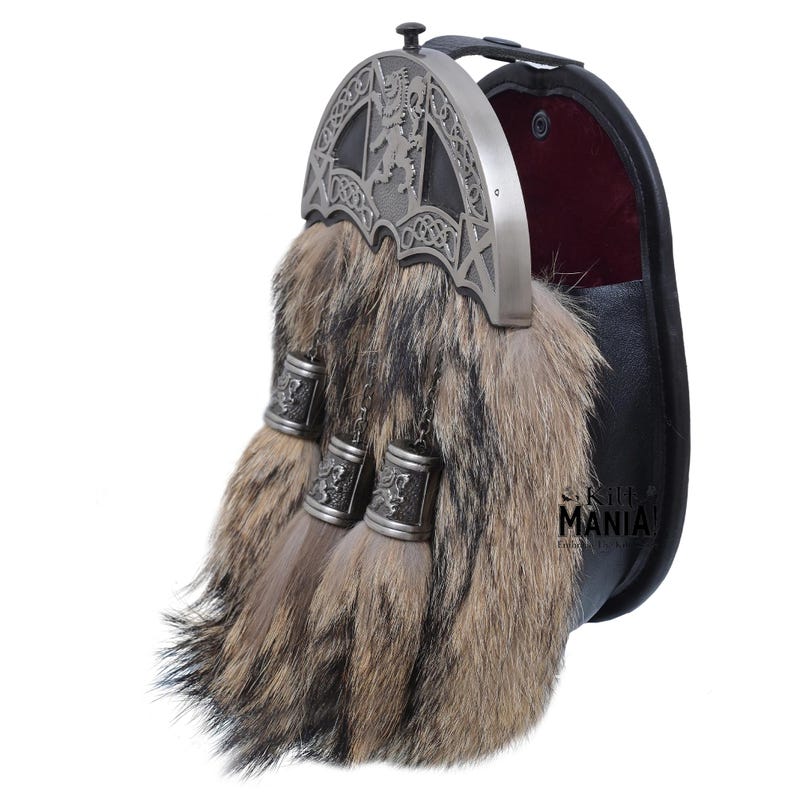 May include: A silver and black kilt pin featuring a lion rampant design, and a brown fur sporran with three tassels. The sporran has a black leather pouch with a red velvet lining.