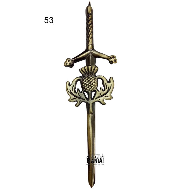 May include: A gold-toned metal kilt pin featuring a sword with a thistle design. The pin is approximately 2.5 inches long.
