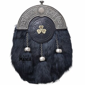 Puede incluir: Un sporran escoc&eacute;s tradicional con un cuerpo de piel oscura y una parte superior de metal decorativa. El sporran presenta una parte delantera de cuero negro con un emblema de tr&eacute;bol dorado. Cadenas y borlas plateadas cuelgan de la parte inferior.