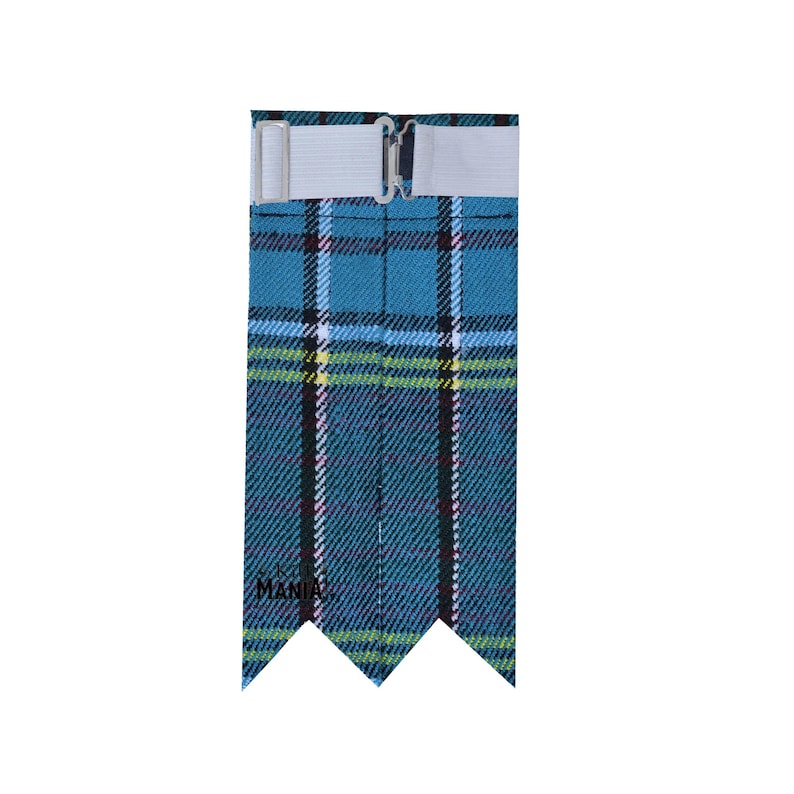 May include: A blue, green, yellow, and white plaid kilt pin with a white elastic strap and a silver buckle. The kilt pin has a three-pointed design at the bottom.