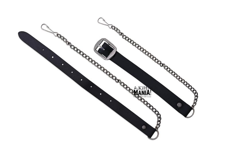 May include: A black leather strap with a silver buckle and a silver chain attached. The strap has a silver hook on one end and a silver loop on the other end.