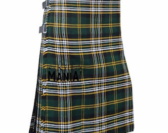 May include: A green, yellow, black, and white plaid kilt with pleats. The kilt has two adjustable straps with buckles. The text "Kilt Mania" is visible on the kilt.