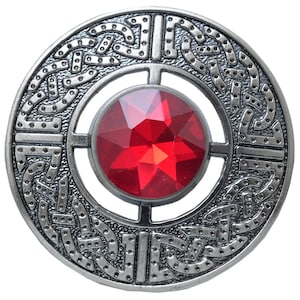Puede incluir: Broche redondo plateado con dise&ntilde;o de nudo celta. Presenta una gran gema roja facetada en el centro. El intrincado trabajo en metal rodea la gema, creando un accesorio detallado y ornamentado.