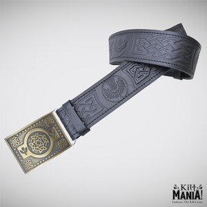 May include: Black leather belt with embossed Celtic knot and thistle designs. The belt features a rectangular brass buckle with intricate floral and geometric patterns. The buckle is attached with a silver-colored metal loop. The belt is from Kilt Mania.