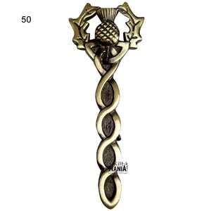 May include: A gold-colored metal pin with a Celtic knot design and a thistle in the center. The thistle is surrounded by a wreath of leaves. The pin is about 5 inches long.
