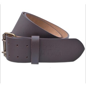 May include: A brown leather belt with a brass buckle and a matching leather loop. The belt has the embossed text "KGH MANIA" on the end. The belt is a classic accessory.
