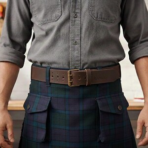 May include: A brown leather belt with a brass buckle is worn over a blue and green plaid kilt. The person is wearing a gray button-down shirt with rolled-up sleeves. The background includes a wooden workbench and tools.