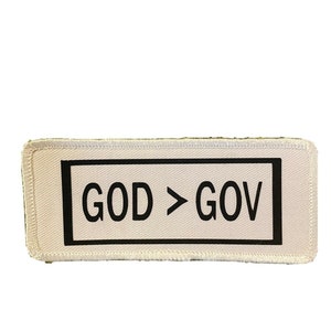 May include: A white patch with black stitching around the edges. The patch has a black rectangle with the text "GOD > GOV" in white.