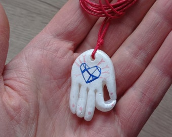 Collana con ciondolo a forma di mano (Gyan mudra) e cuore nel palmo, in porcellana fredda dipinta a mano.