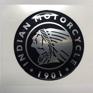 Könnte beinhalten: Runder, schwarzer Aufkleber mit silbernem Schriftzug "INDIAN MOTORCYCLE" am Rand. In der Mitte befindet sich ein silbernes Profil eines indianischen Häuptlings. Das Jahr "1901" steht unten.