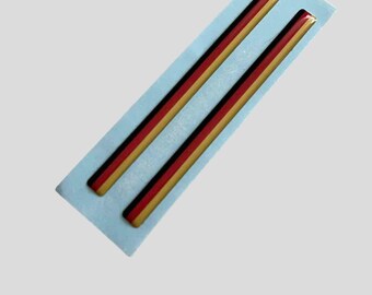 May include: Two thin, black, red, and gold stripes on a blue backing. The stripes are raised and have a glossy finish.