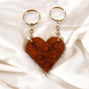 Puede incluir: Un par de llaveros de madera en forma de coraz&oacute;n con anillos y cadenas doradas. Los llaveros est&aacute;n grabados con las letras "L" y "C".