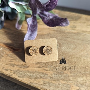 Puede incluir: Un par de pendientes de madera con un diseño geométrico. Los pendientes están en una tarjeta marrón con el texto "Pine Ridge Engraving".
