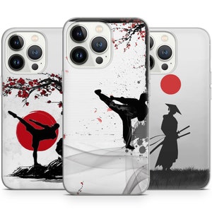 May include: Three iPhone cases with different designs. The first case features a black silhouette of a person kicking in a red circle with a cherry blossom tree in the background. The second case features a black silhouette of a person kicking in a white and gray background with a cherry blossom tree in the background. The third case features a black silhouette of a person holding two swords in a gray and white background with a red circle.