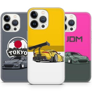 May include: Three phone cases with different designs. The first case is grey with a black and white illustration of a car and the text "TOKYO". The second case is yellow with a black and white illustration of a car. The third case is pink with the text "JDM" in black.
