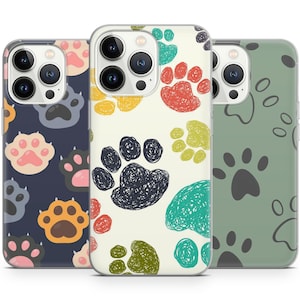 Op de afbeelding: Drie transparante telefoonhoesjes met verschillende potafdrukdesigns. De eerste hoes heeft een donkerblauwe achtergrond met witte, roze en bruine potafdrukken. De tweede hoes heeft een witte achtergrond met kleurrijke potafdrukken. De derde hoes heeft een groene achtergrond met zwarte potafdrukken.