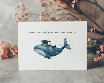 May include: A white card with a blue whale wearing a graduation cap. The text on the card reads "Whale done, you've breached new heights!"