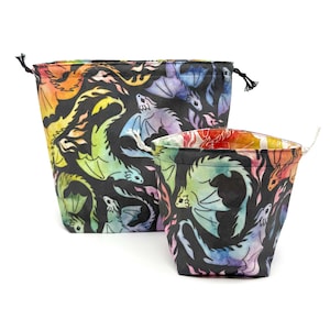 May include: Two drawstring bags with a black background and a colorful dragon pattern. The dragons are in shades of blue, green, yellow, and purple. The bags are different sizes, with a drawstring closure.