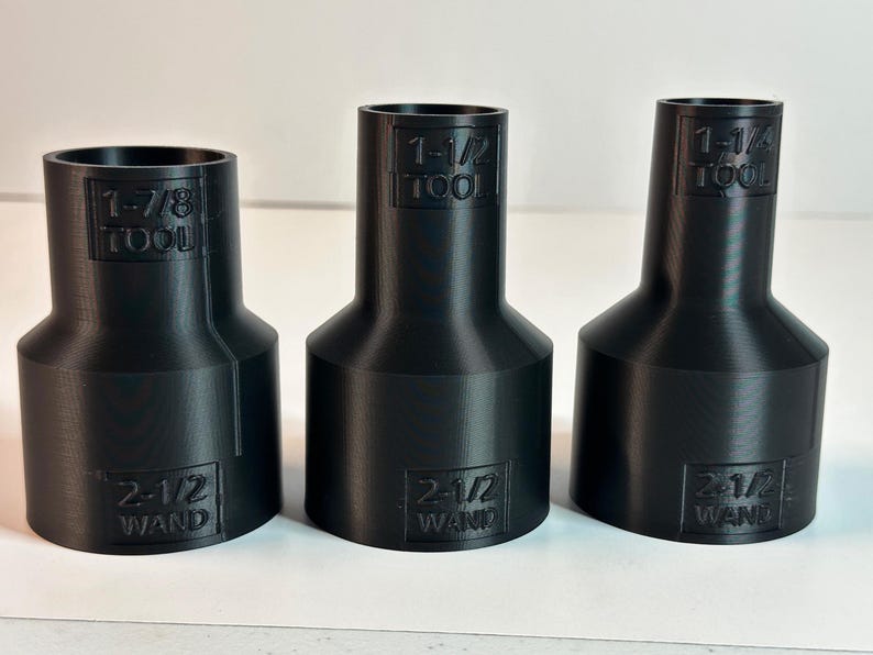 May include: Three black plastic adapters with different sizes. The adapters are labeled with the text "TOOL" and "WAND" and the size of the adapter. The sizes are 1-1/2, 1-1/4, and 1-7/8 inches.