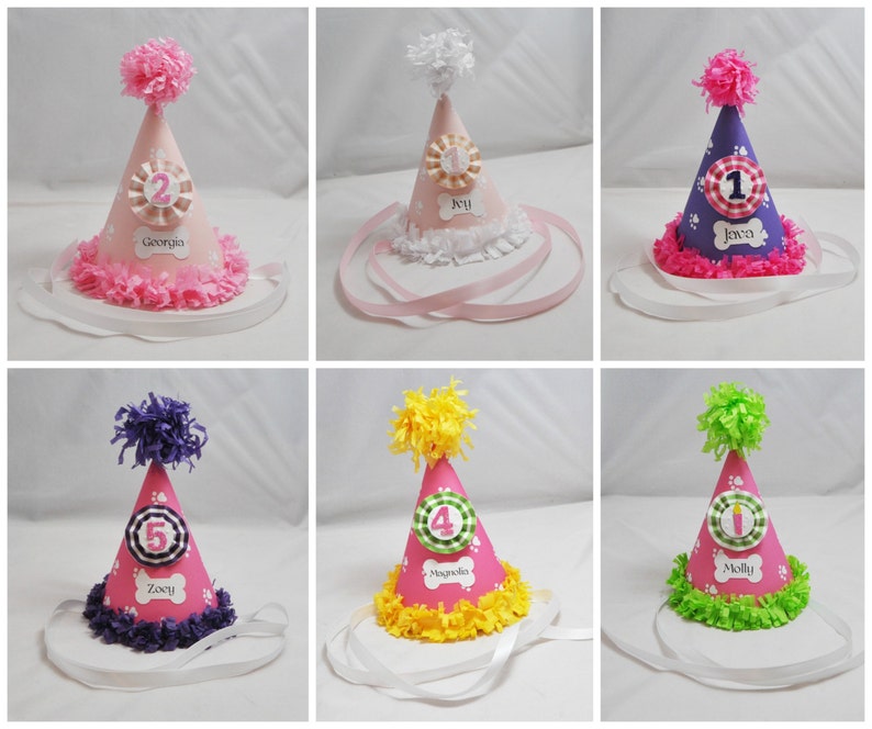 May include: Six pink and white dog party hats with different colored trims and names on each hat. The names are: Georgia, Ivy, Jawa, Zocy, Magnolia, and Molly.