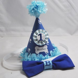 May include: Blue and white dog birthday party hat with a white bone-shaped tag that says "Bentley" and a blue bow tie with a white "B" on it.