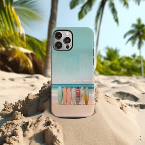An iPhone case with surfboards standing upright on a beach by the ocean stands upright on a beach with palm trees in the background