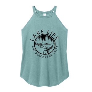 May include: A light teal halter top with a round graphic that says "Lake Life" with a lake scene and a canoe. The text around the graphic says "Cuz Beaches Be Salty".