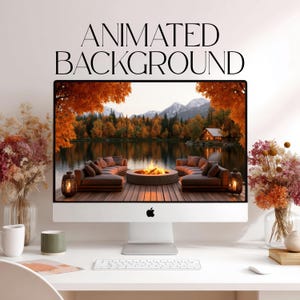 Könnte beinhalten: Ein silberner Desktop-Computer zeigt einen animierten Hintergrund mit einer Hütte am See, einer Feuerstelle und herbstlichen Bäumen. Der Text ANIMATED BACKGROUND steht über dem Bildschirm. Auf dem Schreibtisch stehen zwei Vasen mit Trockenblumen.