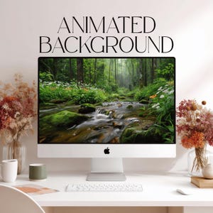 Op de afbeelding: Een zilveren desktopcomputermonitor met een bosbeekscène met groene bemoste rotsen en witte bloemen. De tekst "ANIMATED BACKGROUND" staat boven het scherm. Een wit toetsenbord, een witte mok en boeketten met gedroogde bloemen zijn aanwezig.