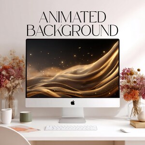 Op de afbeelding: Een zilveren desktopcomputermonitor met een geanimeerde achtergrond van vloeiende gouden golven en fonkelende deeltjes. De tekst ANIMATED BACKGROUND staat boven het scherm gedrukt. De monitor staat op een wit bureau met een wit toetsenbord.