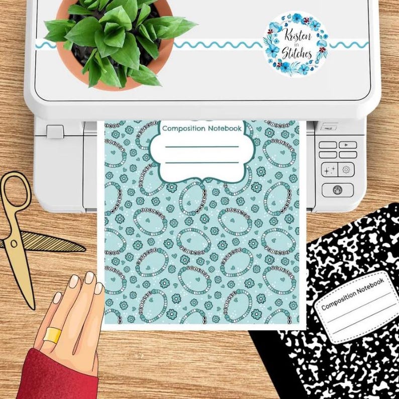 Op de afbeelding: Een compositieboek met een teal patroon van ovale vormen en bloemen wordt afgedrukt vanaf een witte printer. Een gouden schaar en een hand met een gouden ring zijn ook zichtbaar. De printer heeft een sticker met "Kristen in Stitches."