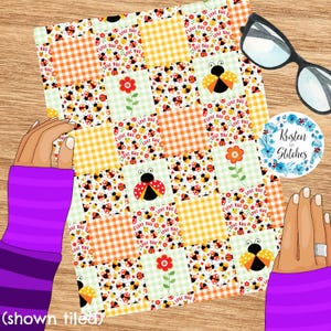 May include: A patchwork fabric with squares of orange gingham, floral, and ladybug patterns. The design includes ladybugs, flowers, and the text "LOVE BUG". A pair of glasses and a sticker with the text "Kristen in Stitches" are also visible.