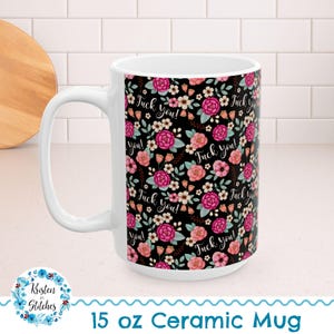 May include: A white ceramic mug with a 15 oz capacity featuring a black background covered in a floral pattern of pink, red, and white flowers with green leaves. The text "Fuck you!" is printed in a white cursive script throughout the design.
