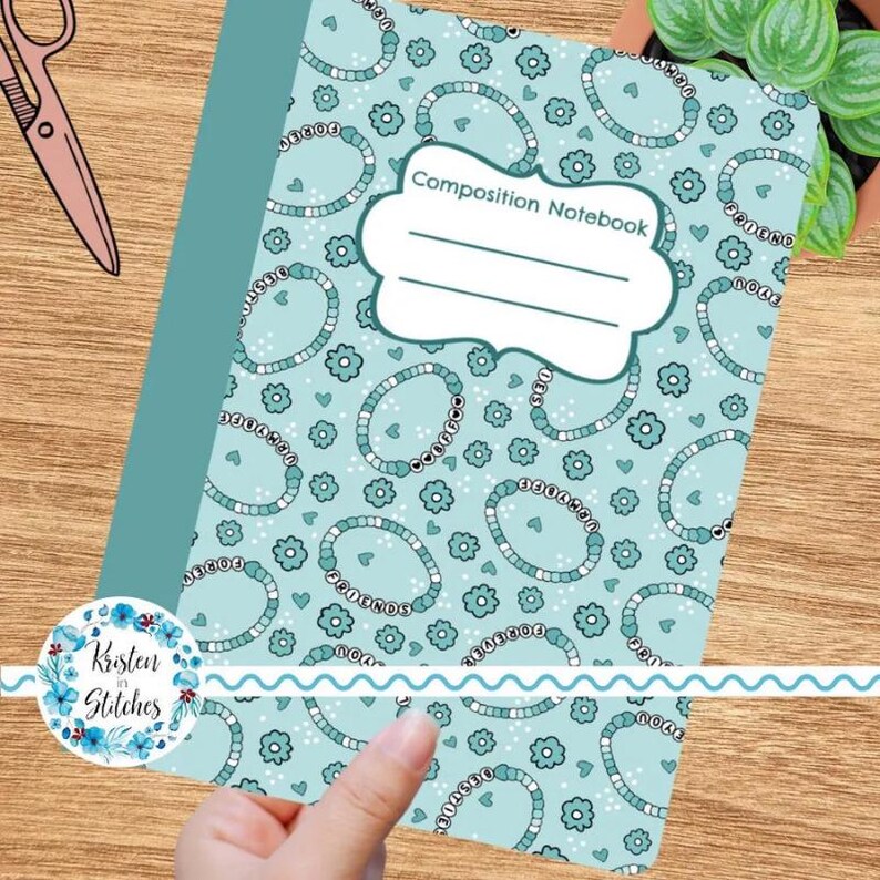 Op de afbeelding: Een notitieboek met een turquoise omslag en een patroon van turquoise en witte armbanden en bloemen. Het notitieboek heeft een wit label met de tekst "Composition Notebook".