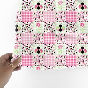 K&ouml;nnte beinhalten: Ein Patchwork-Design mit Quadraten aus rosa Vichy-Karo, Marienk&auml;fern und floralen Mustern. Die Marienk&auml;fer haben schwarze K&ouml;rper und rosa Fl&uuml;gel. Die Worte "Love Bug" sind auf einigen Quadraten aufgedruckt. Das Farbschema ist rosa, gr&uuml;n und schwarz.