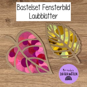 Könnte beinhalten: Zwei blattförmige Bastelsets mit dem Text "Bastelset Fensterbild Laubblätter". Ein Blatt ist mit rosa und roten Kreisen gefüllt, das andere mit gelben und grünen. Ein lila Kreis mit Text und einem Regenbogen ist ebenfalls sichtbar.