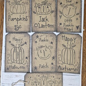 Puede incluir: Un conjunto de etiquetas de papel marrón con ilustraciones de calabazas dibujadas a mano y texto. Las etiquetas presentan frases como "Pumpkins 5¢", "Jack O'Lantern", "Happy Halloween" y "Happy Autumn". Cada etiqueta tiene una estética rústica y vintage.