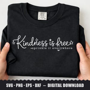 Peut inclure: Un t-shirt noir avec le texte blanc Kindness is free sprinkle it everywhere accompagné de petites étoiles. Le vêtement présente une encolure ronde et une étiquette blanche à l'intérieur du col. Le motif est centré sur le devant.